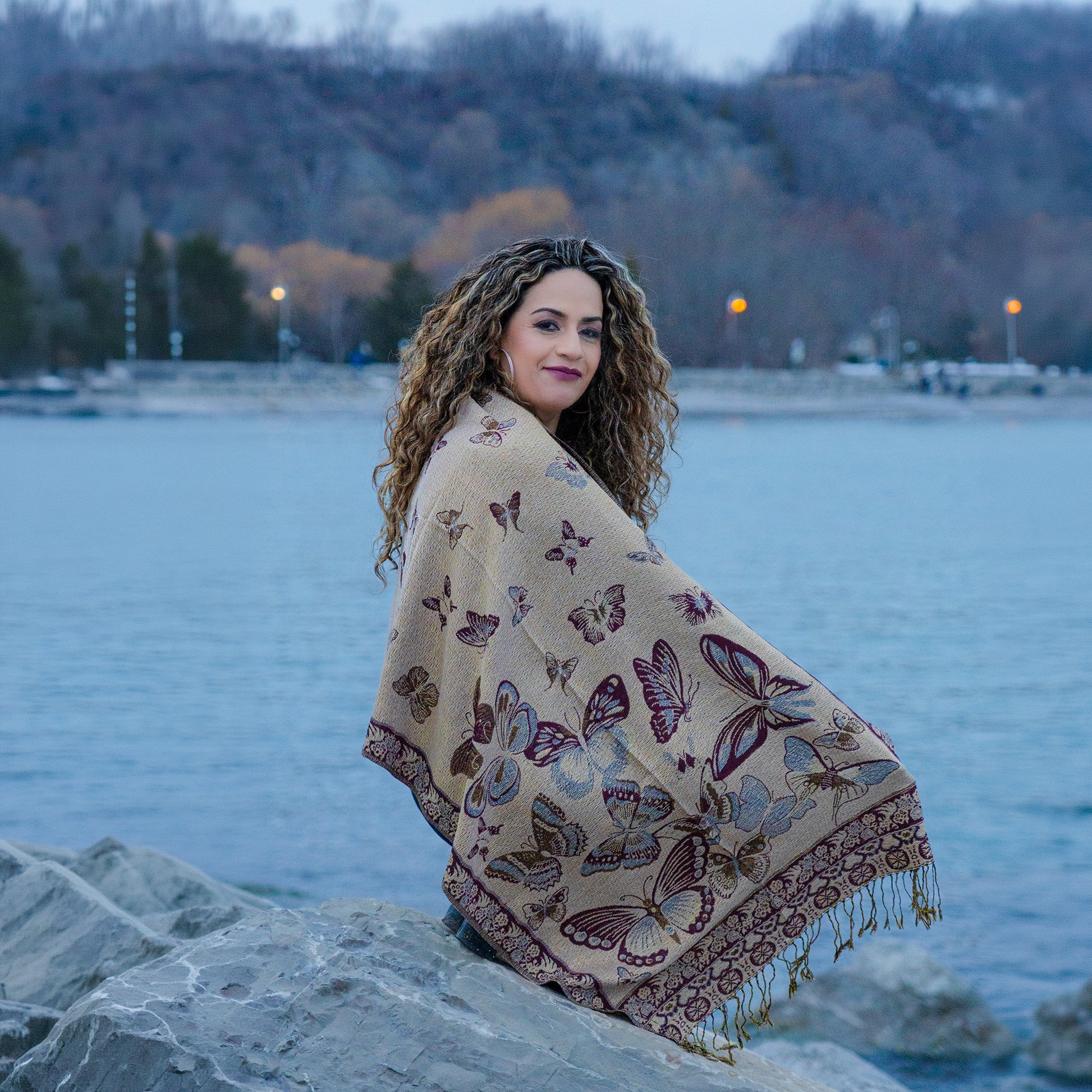 beige monarch butterfly reversible shawl worn by woman sitting by lake in Canada