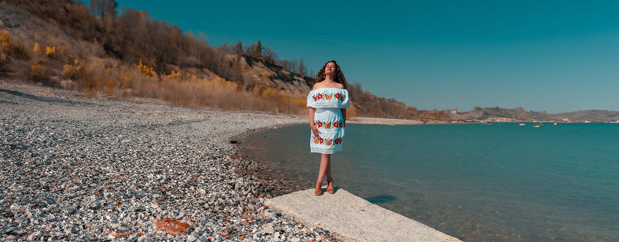 Woman wearing monarch butterfly artisan dress standing by the lake in summer