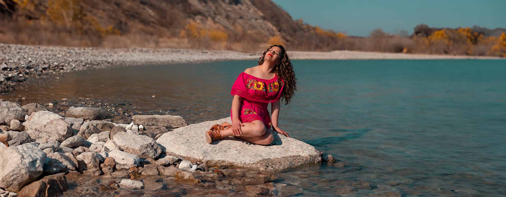 Woman wearing red monarch butterfly artisan dress sitting by the lake