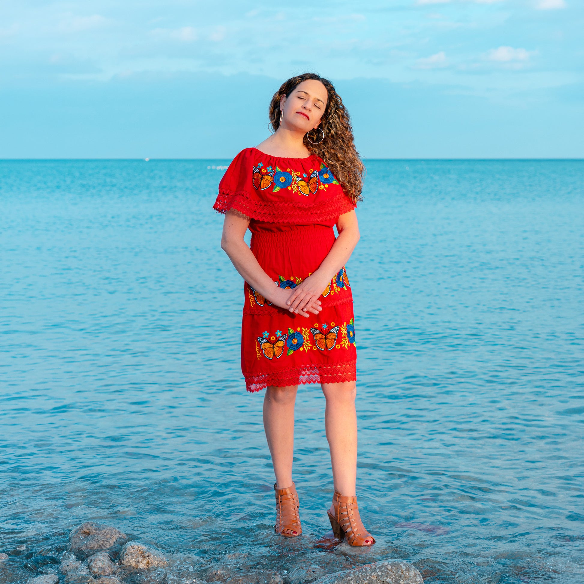 Monarch butterfly embroidered red dress with floral artisan design worn by woman outdoors
