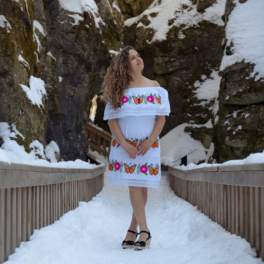 White monarch butterfly embroidered off shoulder dress with floral artisan design worn outdoors in winter setting