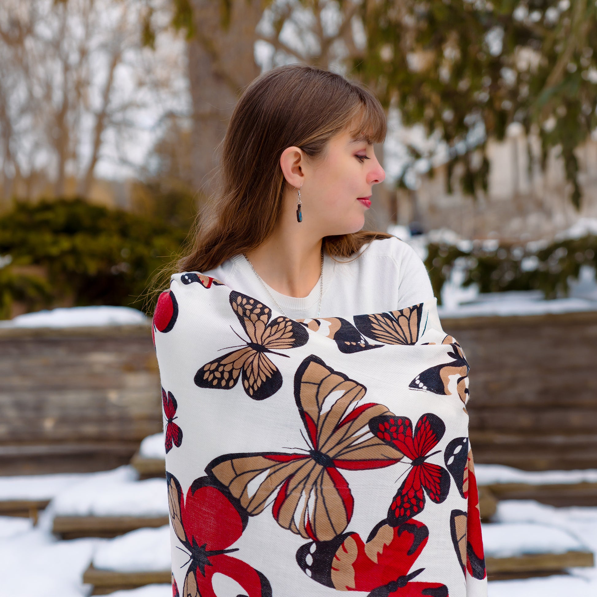 White reversible shawl with red floral and monarch butterfly design worn by woman outdoors